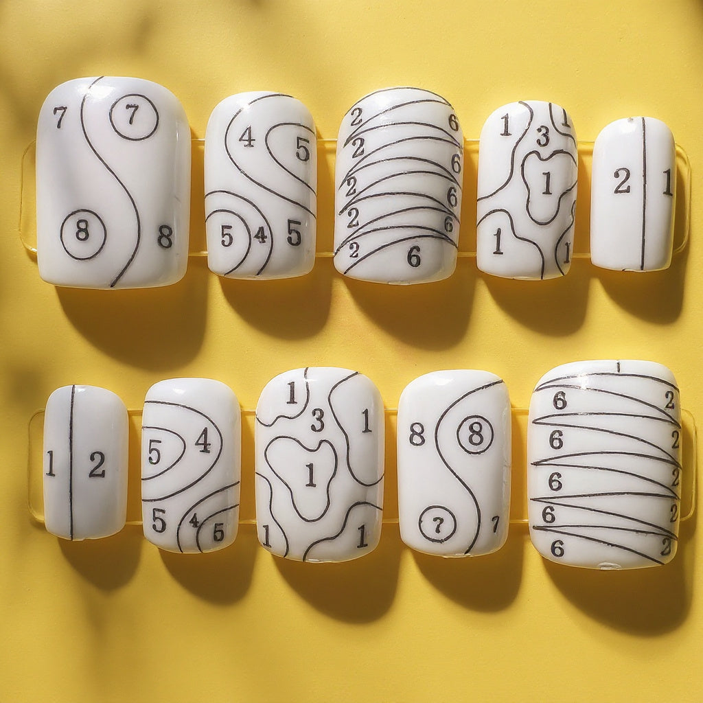 Set of white nail forms with black patterns on a yellow background