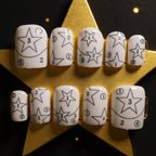 Set of white nail art designs with star patterns on a gold star-shaped stand.