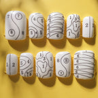 Set of white nail forms with black patterns on a yellow background